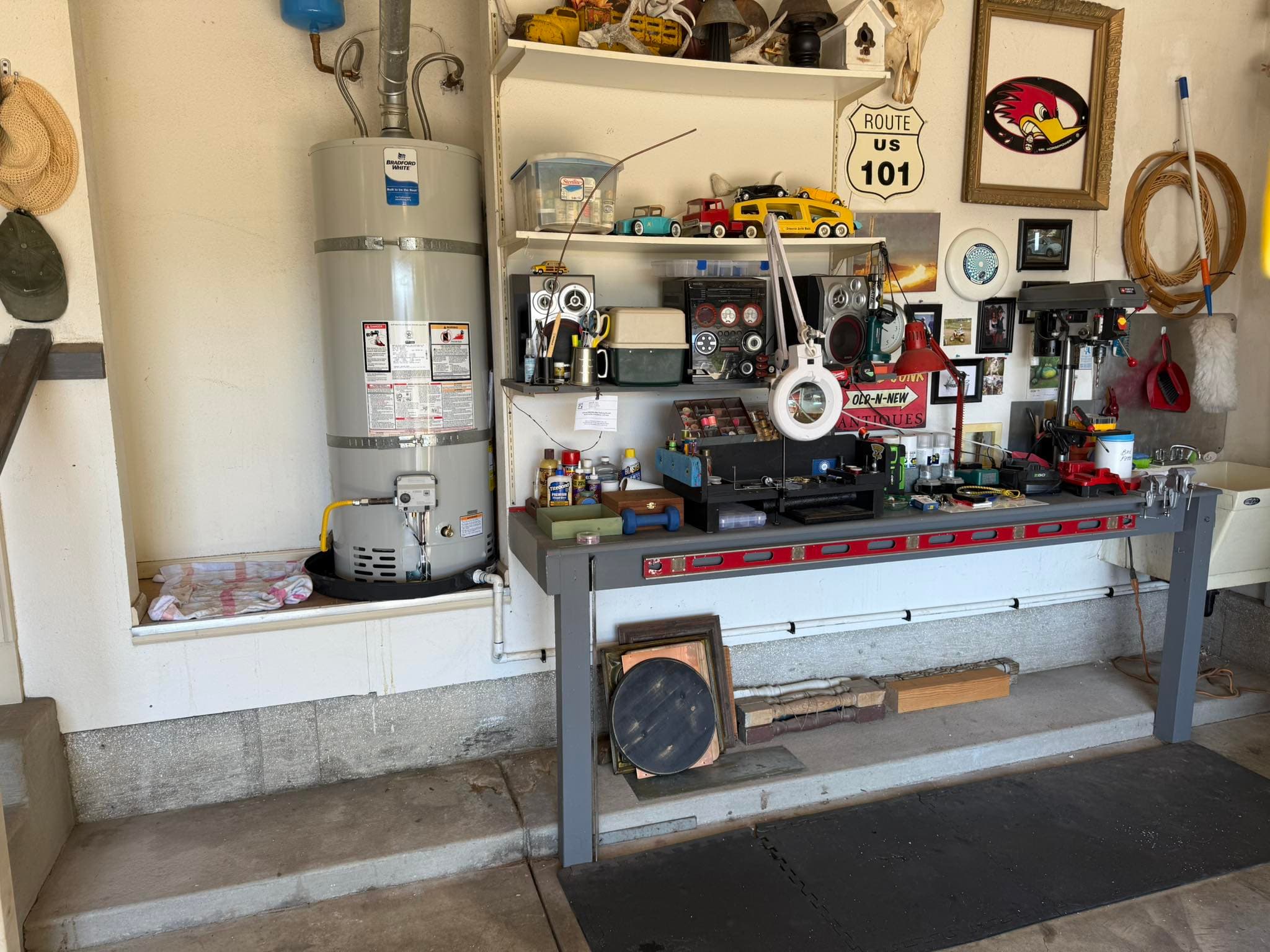 Garage workspace with tools, collectibles, and a vintage water heater on display.