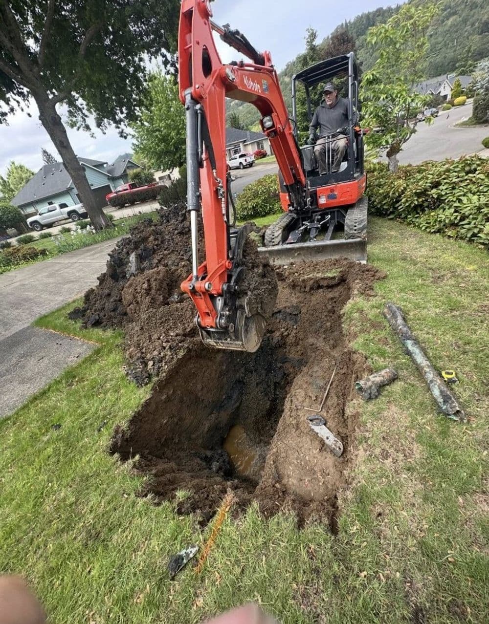 Excavator digging a trench in a residential yard for utility installation or landscaping.